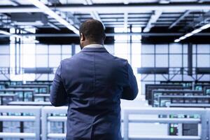 Technician in data center identifying and solving technical bugs related to data center hardware. IT specialist managing, maintaining and securing server hub workspace and supercomputers inside photo