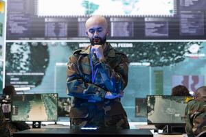 Military staff examining a projection on hologram in command center, working on new defense mission plan. Trooper looking at real time CCTV radar information on a holographic visualization. photo