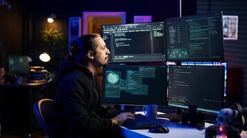 Hacker typing fast on keyboards, rushing to finish developing spyware software, using it to gather data from users computers without their knowledge. Scammer writing malicious code, camera B photo
