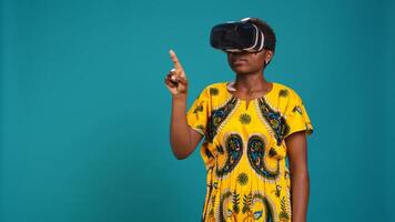 Gorgeous girl in ethnic clothes using vr glasses against blue background, working with high tech 3d experience with virtual reality device. Young woman using smart headset. Camera B. photo