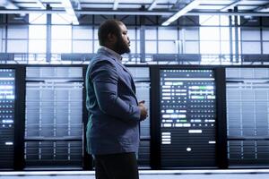 Engineer walking in data center, monitoring system performance, identifying bottlenecks and implementing optimizations to improve efficiency. Server room worker troubleshooting errors photo