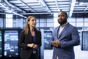 IT staff members in data center monitor system performance, identifying bottlenecks and implementing optimizations to improve efficiency. Teamworking colleagues in server hub troubleshooting damages photo