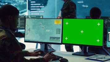 Private monitors national guard activity with military CCTV satellite system, working with a greenscreen display on pc in command center. IT reconnaissance operator tracking ships. Camera A. photo