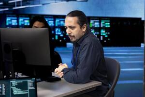 Computer scientists in data center updating systems, protecting servers from damaging software vulnerabilities. Coworkers looking for errors causing infrastructure to slow down photo