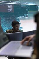 Military personnel in a modern command post work on data processing, integrating real time surveillance in strategic planning for a mission. Security protocols for national defense operations. photo