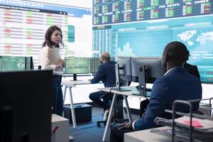 Management associate sharing insight on annual statistics during a chat with an employee, providing initiatives to enhance operational performance metrics. Big data on a screen. photo
