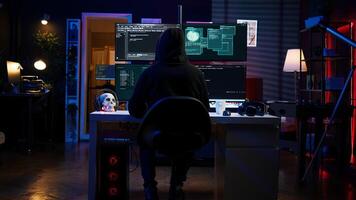 Experienced hacker writing lines of code on computer from underground bunker, tying to get past security systems. Rogue programmer building scripts that can hack devices, camera B photo