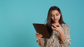 Smiling woman adding payment method on shopping website using tablet, studio background. Jolly person buying online on digital device using credit card, typing data, camera A photo
