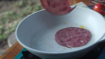 the chef tosses a square thin slice of white melted cheese onto a hot juicy buttery Burger Patty. The food is on the grill pan. the camera moves slowly back and forth, changing focus. video