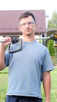 vertical Gardener holding string trimmer on shoulder posing in garden video