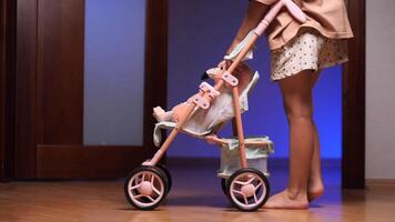 A little girl plays with a toy baby in a doll stroller video