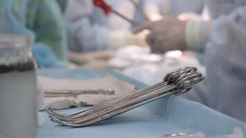 Close-up of surgical instruments in use during an operation, set against the backdrop of a busy operating room. This photo highlights the precision and essential tools involved in a medical procedure video