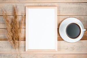 Autumn flat lay. Cup of hot espresso coffee and fallen yellow leaves on wooden background. Empty frame mock up for text. Morning concept. photo