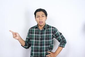 isolated attractive asian young man pointing beside to empty space with confused face and doubtful expression photo