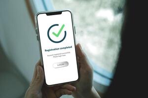Smartphone screen shows Registration completed with Log in to proceed to the next step. The technological concept of project registration or membership application. photo
