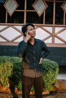 A Southeast Asian man deep in thought, resting his hand on his chin with a contemplative expression photo