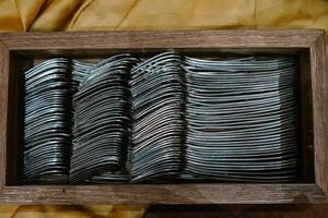 Dozens of silver forks neatly arranged in a rustic wooden holder, ready for dining or display. photo