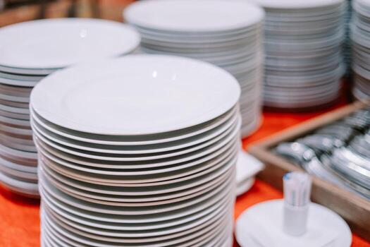 A stack of clean plates and spoons neatly arranged on a buffet table photo