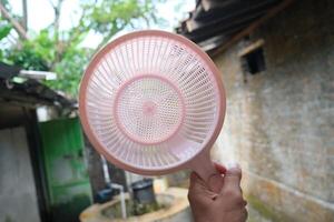 Close-up of a pink plastic colander held by a hand. photo