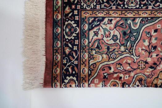 Close-up of a rug's edge with intricate floral pattern and fringe. photo