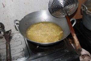 Deep frying food in a large metal pan on a stovetop. photo