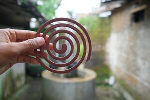Close-up of a brown mosquito repellent coil held in a hand. photo