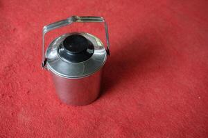 Silver thermos with handle on red background. photo