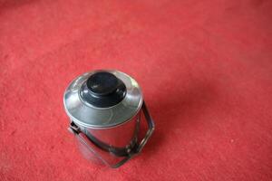 Stainless steel container with a black lid on a red background. photo
