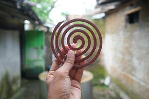 Close-up of a hand holding a mosquito repellent coil. photo