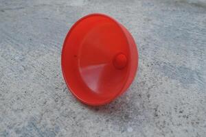 Red plastic funnel on a concrete surface. photo