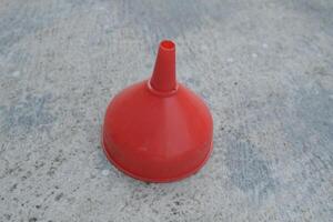 Red plastic funnel on a gray surface. photo