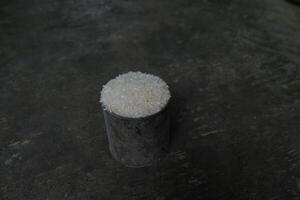Uncooked white rice in a metal cup on a dark rustic background. photo