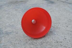 A red plastic funnel lies on a textured gray surface. photo
