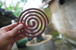 Hand holding a brown mosquito coil. photo