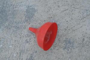Red plastic funnel on a concrete surface. photo