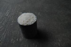 A close-up of a cup of uncooked white rice. photo