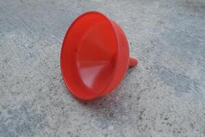 Red plastic funnel on grey concrete surface. photo