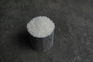 White rice grains in a metal cup on a rustic surface. photo