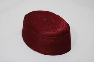 A close-up of a maroon woven cap. photo