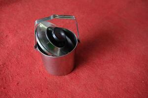 Silver thermos with a lid, on red background. photo