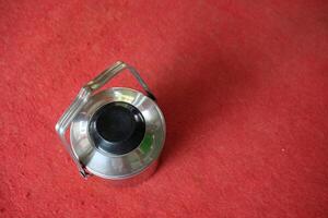 Silver container with a black lid on a red background. photo