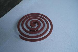 Close-up of a brown mosquito repellent coil on a white surface. photo