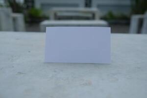 Blank white card on a concrete surface with a blurred background. photo