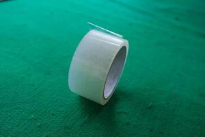A roll of clear adhesive tape on a green surface. photo