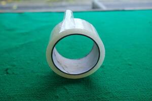 Close-up of a roll of clear tape on a green surface. photo