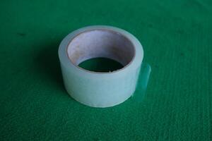 A roll of transparent tape on a green surface. photo