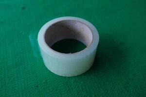 Roll of clear tape on green surface. photo