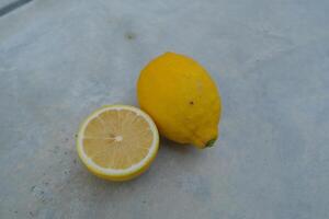A whole lemon and a cut lemon slice on a grey surface. photo