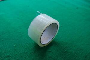 A roll of clear tape on a green surface. photo