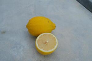 A whole lemon and a slice on a grey surface. photo